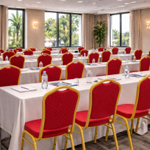 Konferenzstuhl mit roter Polsterung und goldenem Gestell.